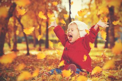 happy little child, baby girl laughing and playing in autumn